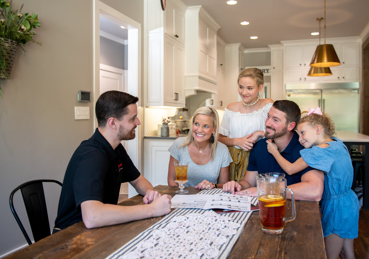 HVAC technician speaking with a family inside a home